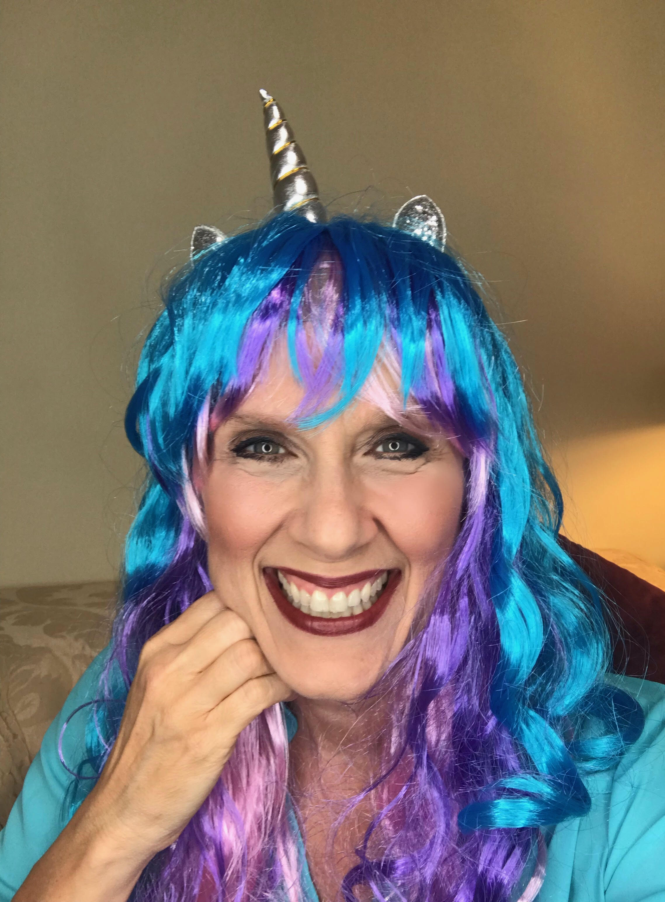 A woman with blue hair and unicorn horn on her head.